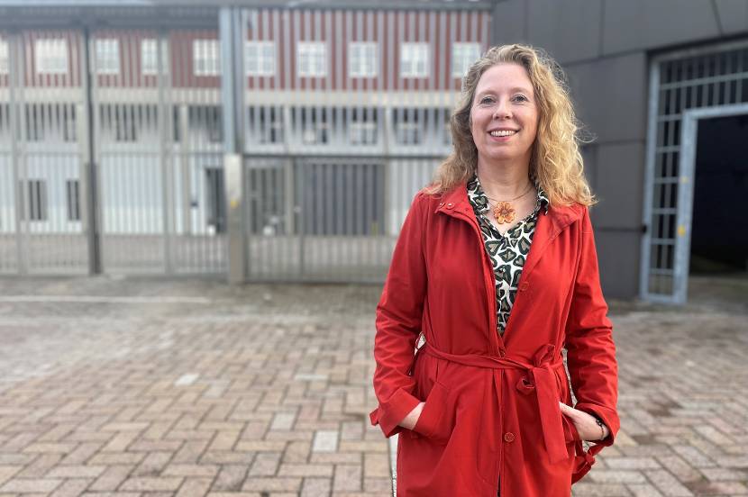 Medewerker poseert buiten voor de gevangenispoort